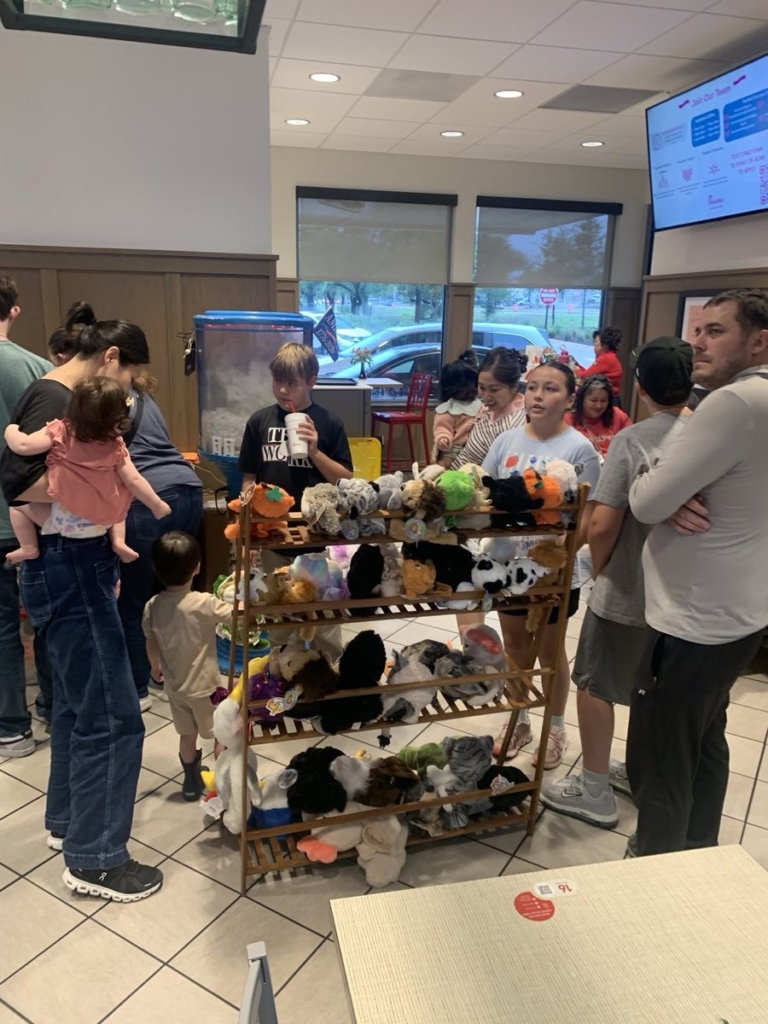 Families choosing stuffed animals from the rack at Kids Night, Chick-fil-A Georgetown